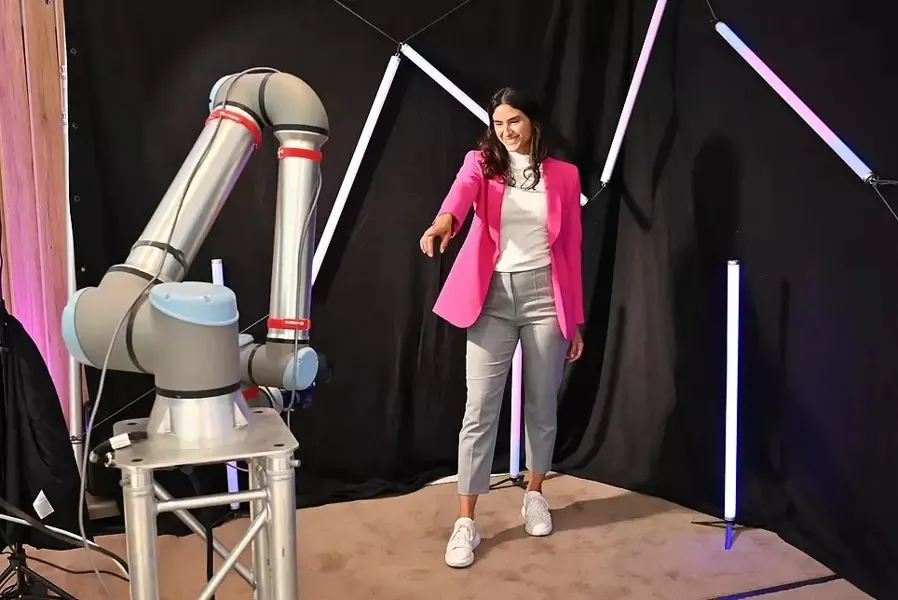 Gast posiert im Neonlicht vor dem Glambot-Roboterarm